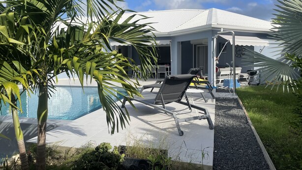 Ein modernes Haus mit Pool, Sitzgelegenheiten im Freien und einem Garten.