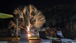 Ein Poolbereich mit Liegestühlen, einem Feuerplatz und einer Steinmauer im Hintergrund.