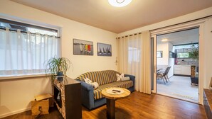 Una sala de estar con sofá, mesa de centro, chimenea y puerta corrediza de vidrio que da a un balcón.