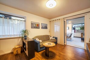 Ein Wohnzimmer mit einer Couch, einem Couchtisch, einem Kamin und einer Schiebetür, die auf einen Balkon führt.