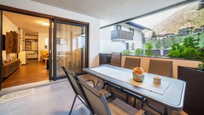 Un comedor moderno con una mesa y sillas, vista a una montaña y cocina al fondo.