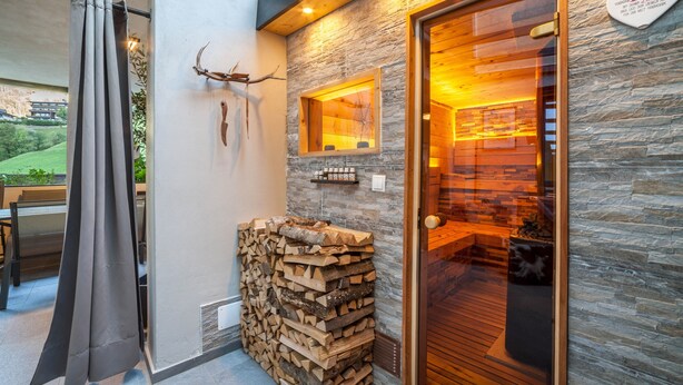 Un interior moderno con una pared de piedra, una puerta de madera y una pila de leña.