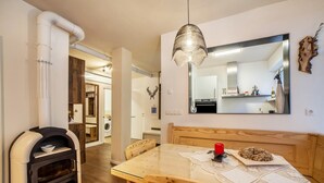 Una cocina moderna con horno empotrado, mesa de comedor de madera y una lámpara colgante.