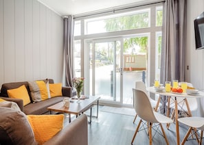 A modern living room with a sofa, coffee table, and dining area with chairs and breakfast items.