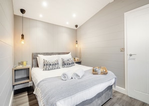 A modern bedroom with a bed, bedside tables, a nightstand, a lamp, and a door. - 1 bedroom accommodation in Snowdonia (Snowdonia)