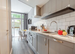 A modern kitchen with a large island, a built-in oven, and a flat-screen TV. - 2 bedroom accommodation in Snowdonia (Snowdonia)