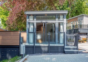 A modern building with a glass entrance, a wooden fence, and a paved area in front. - 1 bedroom accommodation in Snowdonia (Snowdonia)