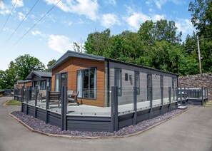 A modern RV-style building with a covered patio area, large windows, and a stone wall backdrop.