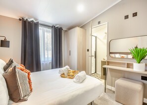 A hotel room with a bed, a bathroom with a mirror, and a small plant on the vanity.
