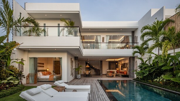 A modern two-story house with a swimming pool, outdoor seating, and a balcony.