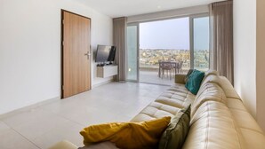 Een moderne woonkamer met een bank, een televisie en een balkon met uitzicht op de stad.