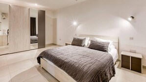 Een moderne slaapkamer met een groot bed, een nachtkastje en een spiegel.