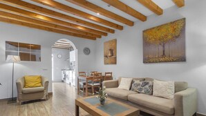Una sala de estar moderna con techo de madera, un sofá, una mesa de centro y un comedor con sillas y una mesa.