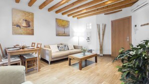 Un salón amplio con vigas de madera, un sofá, una mesa de comedor y una mesa de centro.