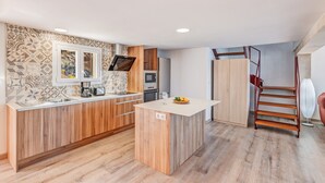 Una cocina moderna con una isla central, electrodomésticos integrados y suelo de madera.