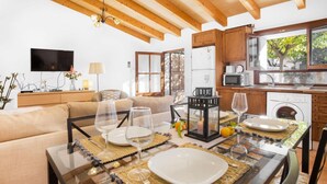 A dining area with a glass table, chairs, and a kitchen in the background. - Air-Conditioned Holiday Home with Pool, Terrace, Mountain View & Wi-Fi (Sóller)