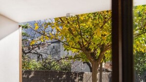 A dining area with a table set for two, chairs, and a view of a tree and outdoor seating. - Air-Conditioned Holiday Home with Pool, Terrace, Mountain View & Wi-Fi (Sóller)