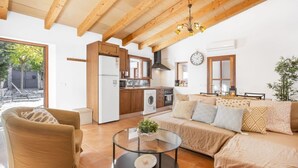A living room with a sofa, armchair, and coffee table, a kitchen with appliances, and a dining area with a table and chairs. - Air-Conditioned Holiday Home with Pool, Terrace, Mountain View & Wi-Fi (Sóller)