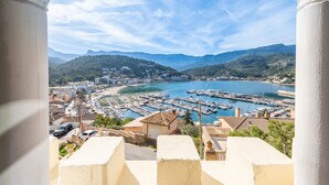Un pueblo costero con un puerto deportivo, edificios y montañas al fondo.