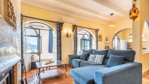 Una sala de estar con sofá, una mesa de centro de vidrio y una chimenea.