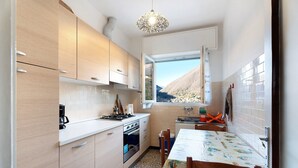 A kitchen with wooden cabinets, a dining table with a tablecloth, and a window with a mountain view.
