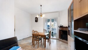 A dining area with a wooden table and chairs, a black sofa, and a television.
