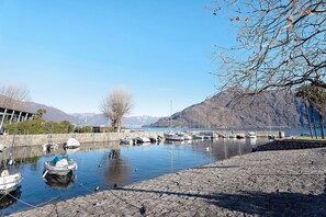 A marina with boats docked, a stone walkway, and mountains in the background. - Apartment "Casa Elsa" with Mountain View, Balcony & Wi-Fi (cannobio)