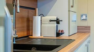 A kitchen with a coffee machine, a paper towel dispenser, and a sink.