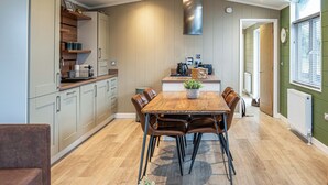Una cocina moderna con comedor, piso de madera y un ventanal con persianas.