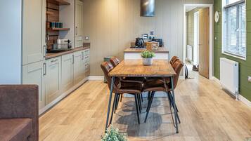 Une cuisine moderne avec un coin repas, un plancher en bois et une grande fenêtre équipée de stores.