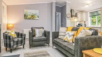 A modern living room with a grey sofa, two armchairs, a patterned rug, and a painting on the wall.