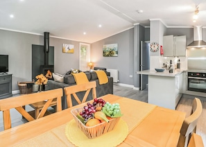 A modern apartment with a dining area, kitchen, living room, and a fireplace. - Deluxe lodge with one master double with an en suite shower and one twin. (Cartmel)