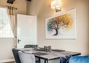 A dining area with a table set for four, a white door, and a colorful abstract painting on the wall.