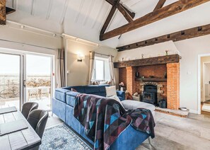 A cozy living room with a blue sofa, a fireplace, and a dining area with a table and chairs.