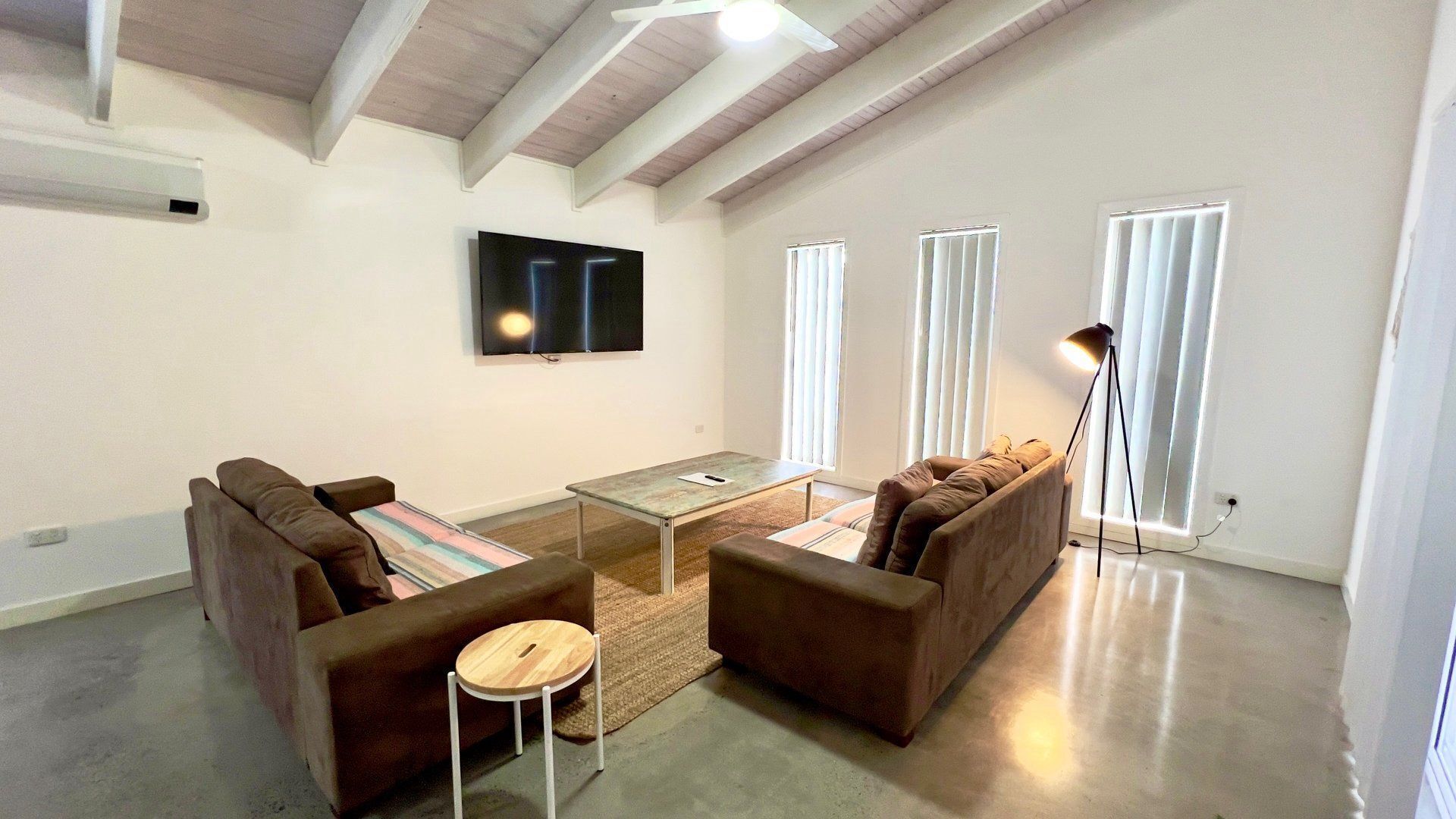 A modern living room with a flat-screen TV, two sofas, a coffee table, and a floor lamp.