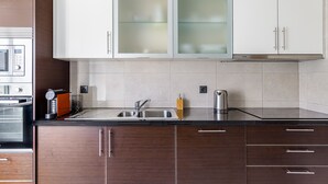 Una cocina moderna con armarios de madera oscura, un lavamanos de acero inoxidable y un horno empotrado.