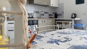 A modern kitchen with white cabinetry, a tiled backsplash, and a dining area with a table set for two. - Holiday Home "Casa OriMar 419" with Shared Pool and Wi-Fi (Badesi)