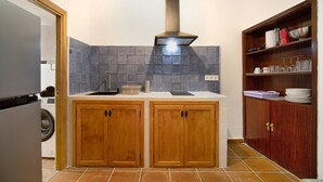 Eine Küche mit Holzausbau, einem eingebauten Herd, einer Waschmaschine und einem Schrank mit Geschirr.