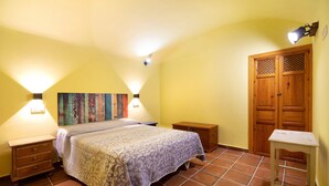 Ein Schlafzimmer mit einem Bett, Nachttischen, einer Kommode, einer Wandlampe und einem Holzschrank.