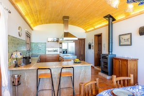 A kitchen with a central island, bar stools, a stove, and a dining area with a table and chairs.