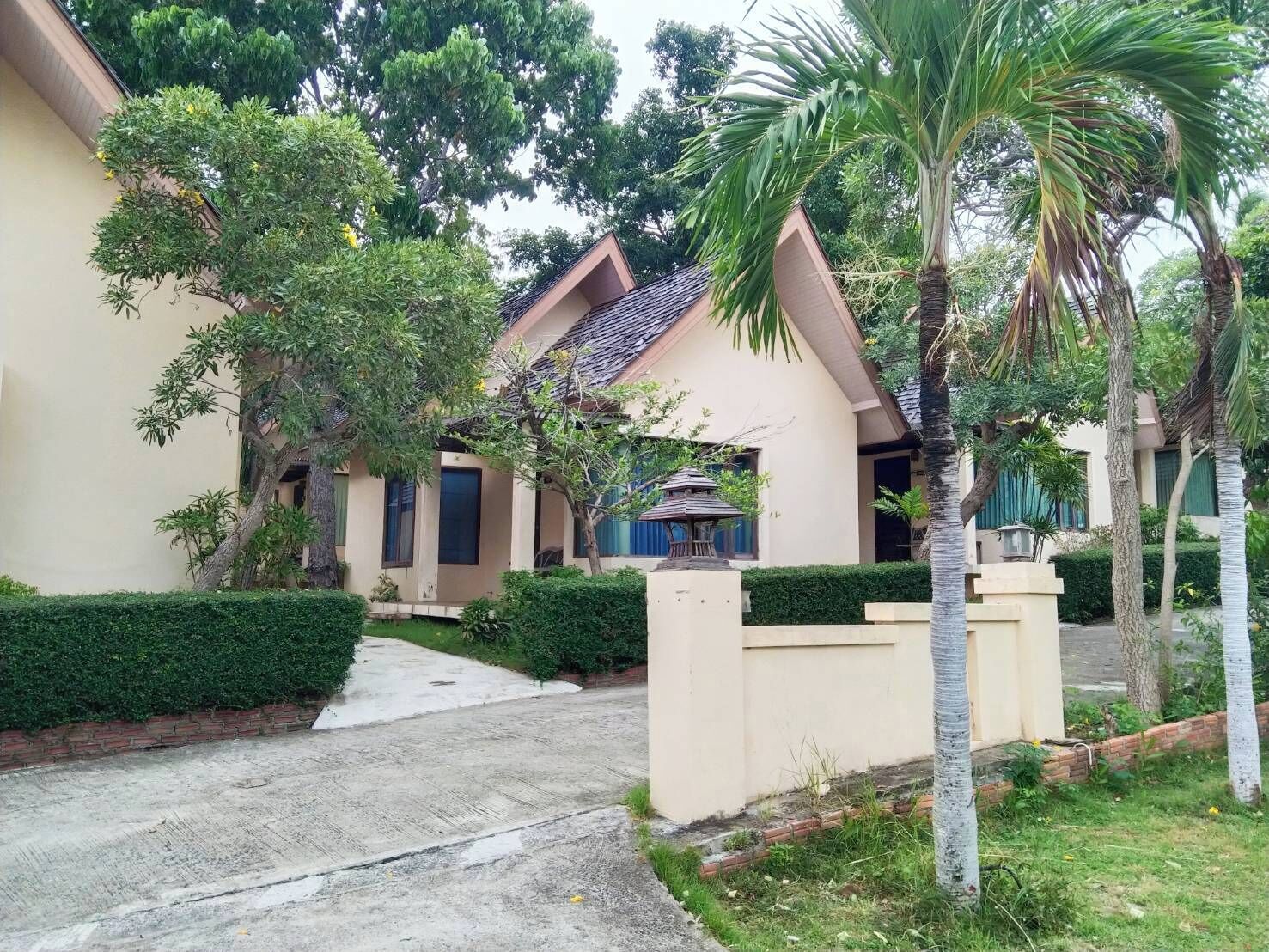A two-story building with a tiled roof, a covered patio, and a paved driveway.