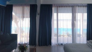 A hotel room with a bed, a sofa, and a view of the sea. - Samui Tonggad Resort (Koh Samui)
