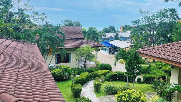 A residential area with houses featuring red-tiled roofs, surrounded by lush greenery and palm trees. - Samui Tonggad Resort (Koh Samui)