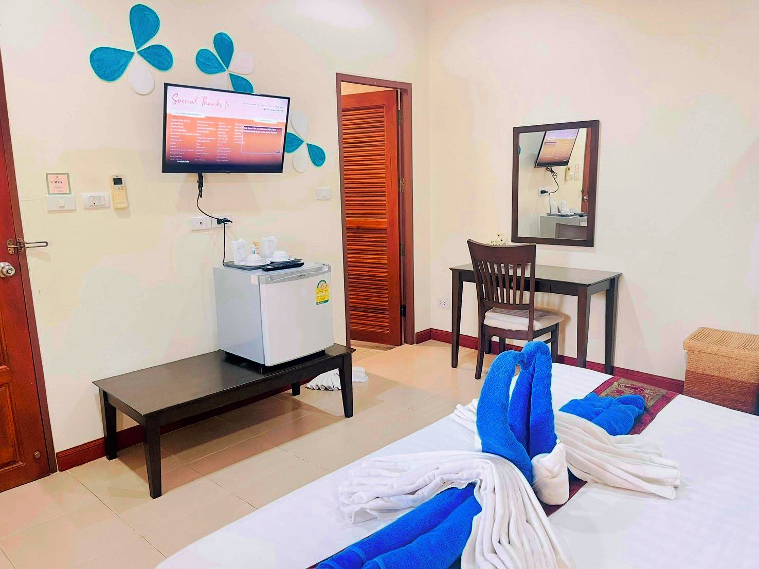 A hotel room with a bed, a desk, a chair, a television, and a minibar.