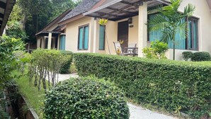 A bungalow with a tiled roof, a covered porch, and a well-maintained garden with hedges and plants. - Samui Tonggad Resort (Koh Samui)