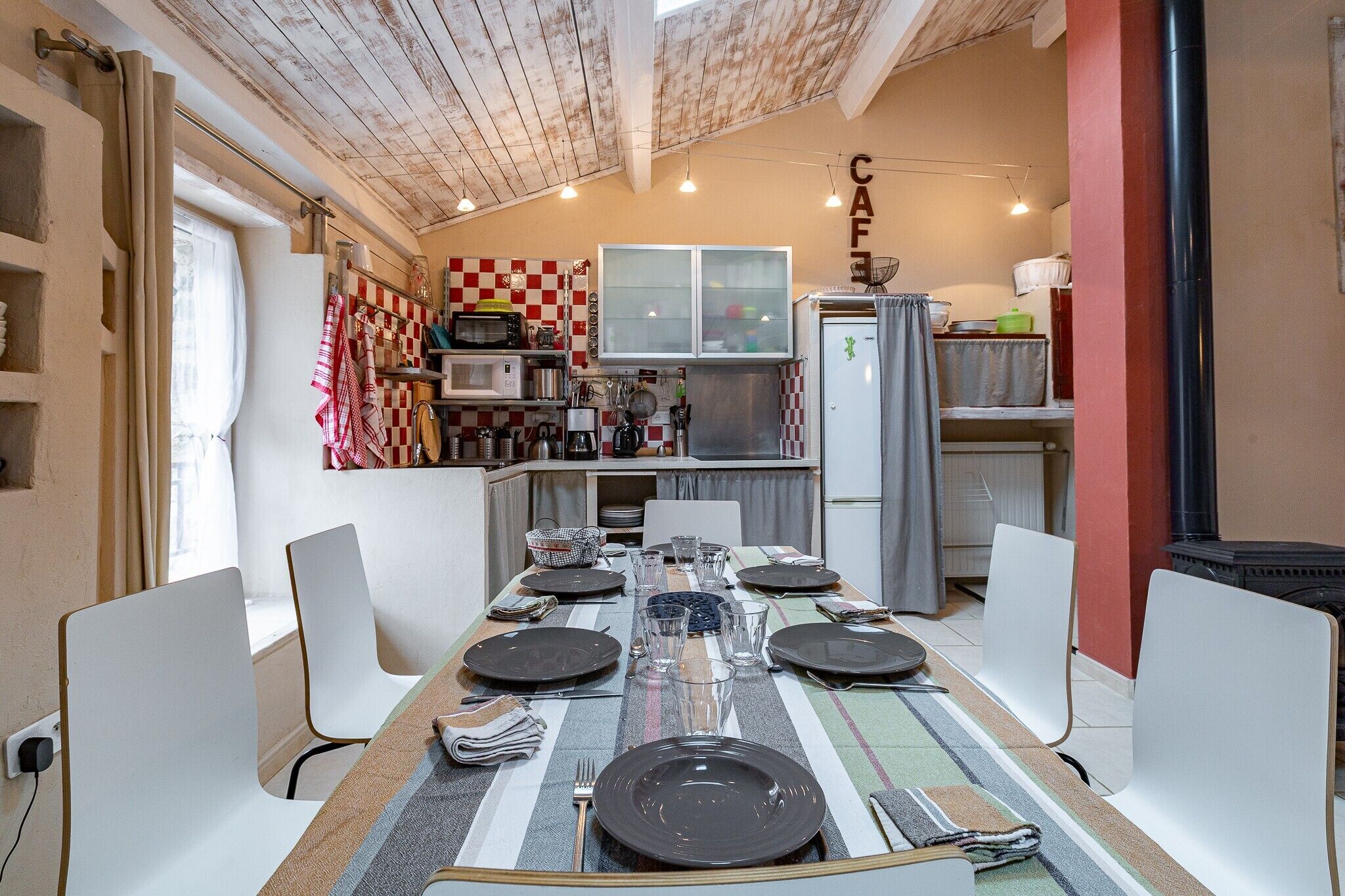 A dining area with a table set for four, a kitchen in the background, and a sign that reads 'CAFE'.