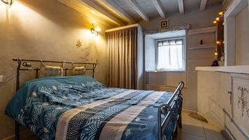 Une chambre à coucher avec un lit, des lampes de chevet, une fenêtre avec des rideaux et une petite étagère.