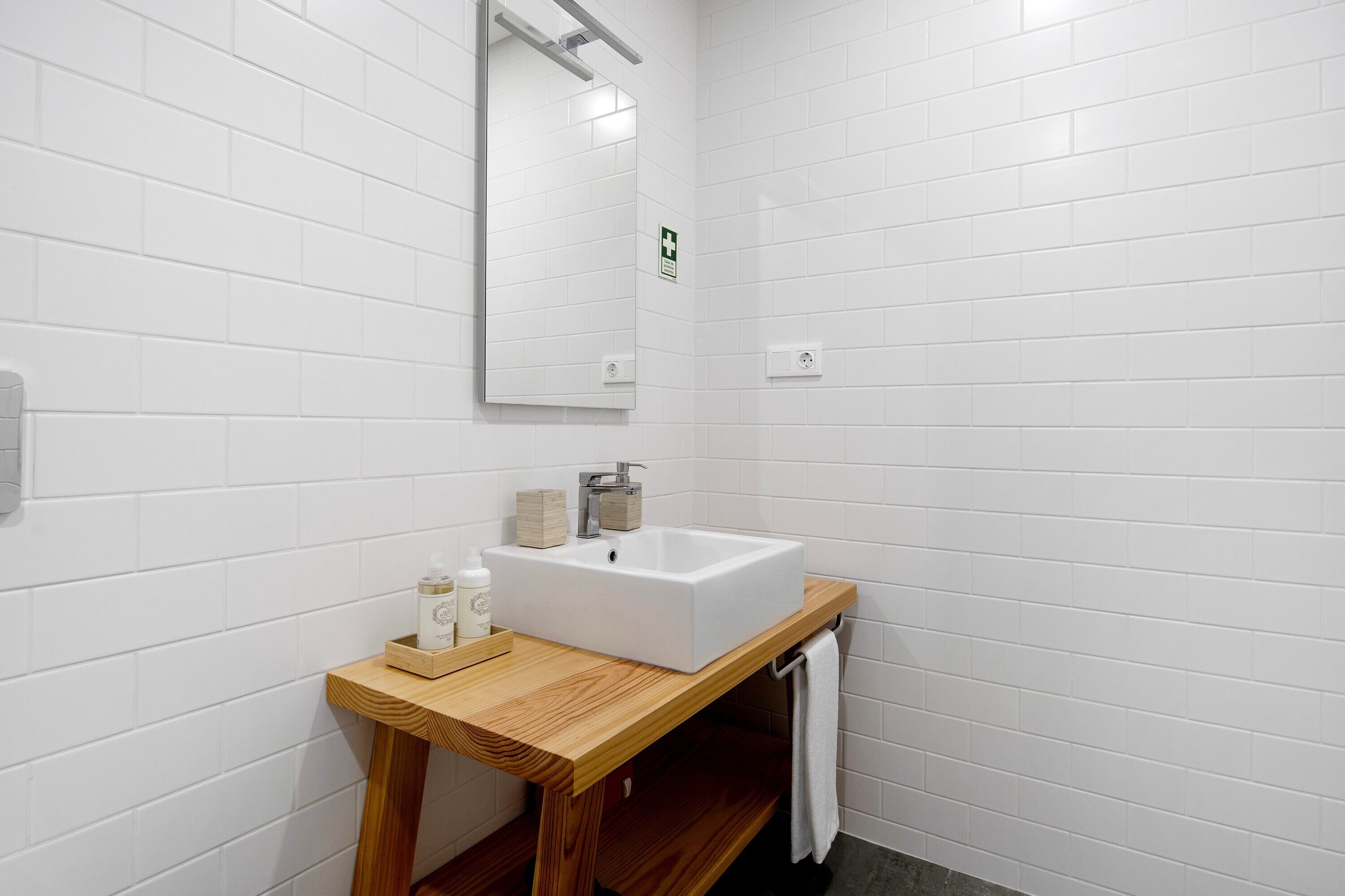 A bathroom with a white sink, wooden vanity, and a mirror.