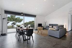 A modern living room with a dining area, a sofa, and a TV. - Apartment "Rocha do Mar 2" with Sea View, Shared Pool & Wi-Fi (Biscoitos)