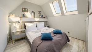A bedroom with a bed, bedside table, lamp, and a skylight.